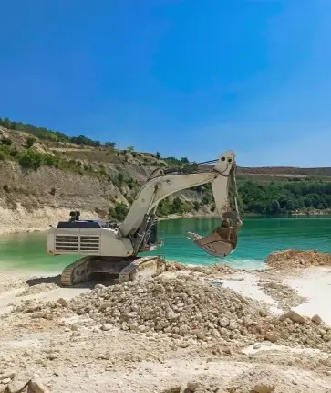A large excavator on the shore of a lake.