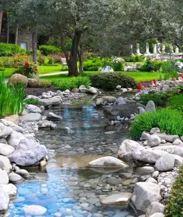 A stream in a garden surrounded by rocks and flowers.