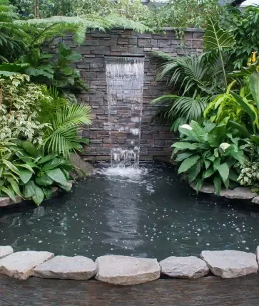 A pond with a waterfall in the middle of a garden.